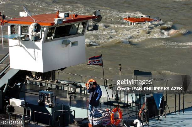 Une personne téléphone sur un bateau pousseur qui tente de maintenir les deux barges bloquées contre la pile d'un pont, le 19 janvier 2004 sur le...