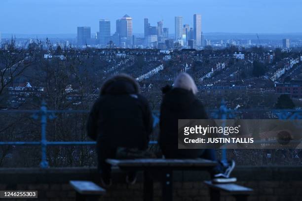 People look out at a view of residential properties with the skyline of London's financial district behind, seen from Alexandra Palace in London on...