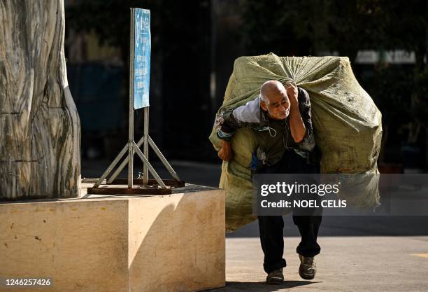 An elderly man carries a bag of recyclable materials on his back in Ruili, west Yunnan Province, on January 13, 2023. - The city of Ruili is slowly...