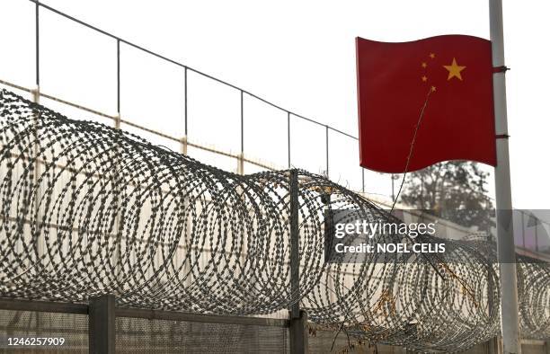 This photograph taken on January 14 shows a part of a border wall between China and Myanmar with barbed wire and a Chinese national flag, in Ruili,...