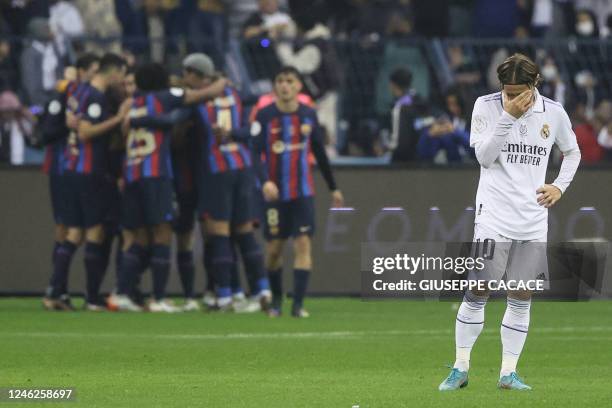 Real Madrid's Croatian midfielder Luka Modric reacts as Barcelona's Polish forward Robert Lewandowski celebrates after scoring his team's second...