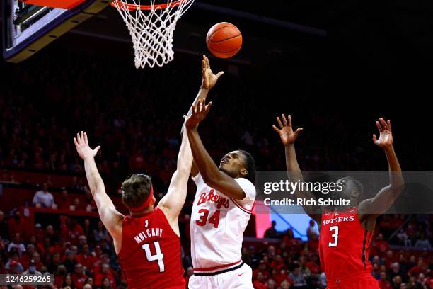 Felix Okpara of the Ohio State Buckeyes attempts a shot as Paul Mulcahy and Mawot Mag of the Rutgers Scarlet Knights defend during the first half of...
