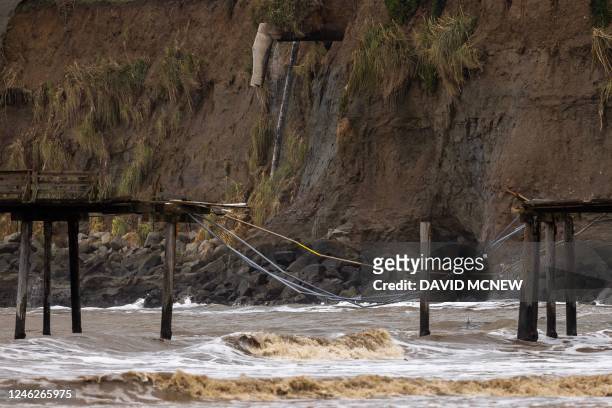 An eroding sea cliff is seen behind the Capitola Wharf, damaged after recent storms in Capitola, California, on January 15, 2023. - Soggy...