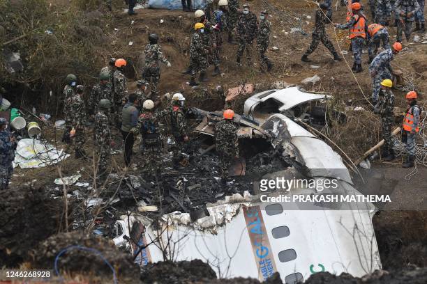 Rescuers inspect the wreckage at the site of a Yeti Airlines plane crash in Pokhara on January 16, 2023. - Nepal observed a day of mourning on...