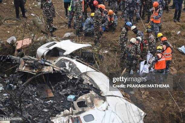 Graphic content / Rescuers prepare to carry the body of a victim who died in a Yeti Airlines plane crash in Pokhara on January 16, 2023. - Nepal...