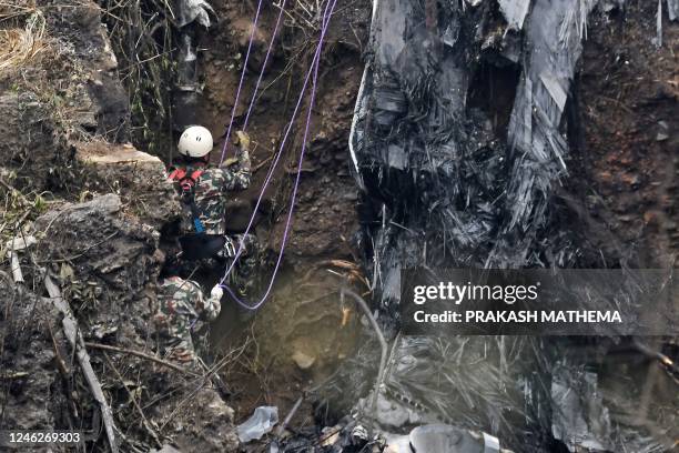 Rescuers inspect the wreckage at the site of a Yeti Airlines plane crash in Pokhara on January 16, 2023. - Nepal observed a day of mourning on...