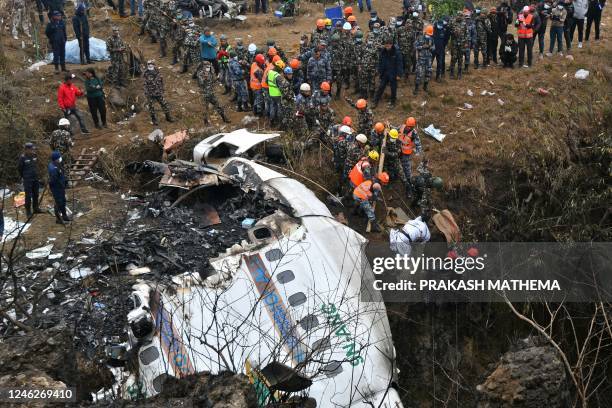 Graphic content / TOPSHOT - Rescuers pull the body of a victim who died in a Yeti Airlines plane crash in Pokhara on January 16, 2023. - Nepal...