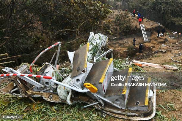 Rescuers inspect the wreckage at the site of a Yeti Airlines plane crash in Pokhara on January 16, 2023. - Nepal observed a day of mourning on...