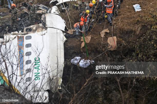 Graphic content / Rescuers pull the body of a victim who died in a Yeti Airlines plane crash in Pokhara on January 16, 2023. - Nepal observed a day...