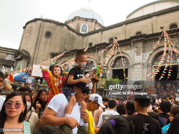 Father carries his son on his shoulder as they leave Tondo Church during the feast of Señor Santo Niño in Tondo, Manila. Catholic devotees flock to...