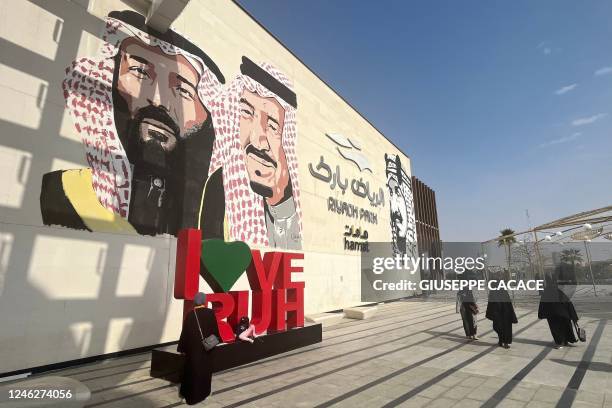 Saudi women walk past a mural depicting Saudi King Salman bin Abdulaziz , Crown Prince Mohammed and King Abdulaziz bin Saud , the founder of the...