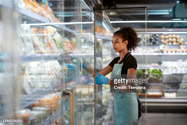 one grocery store employee opening the frideg door - consumerism stock pictures, royalty-free photos & images