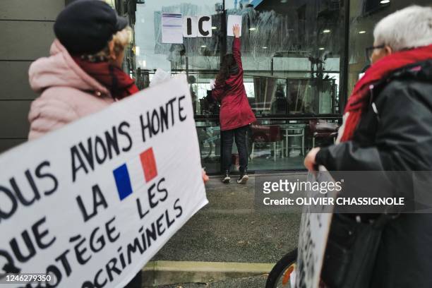 Members of the Be Brave France hold a slogan reading in French "We are ashamed that France protects pedocrminals" during a rally in Lyon on January...