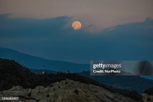 Full Wolf Moon in Greece lights up the January clear winter sky with reflection on the sea in Halkdiki in Northern Greece during the magic hour. The...