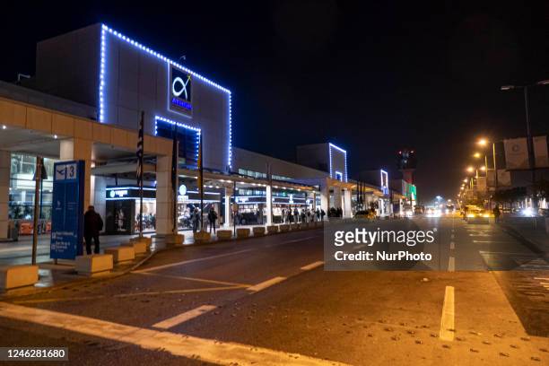 Exterior view of Athens International Airport with the illuminated logo on the building and the control tower, while cars are arriving to leave...