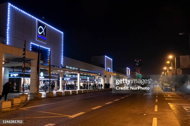 Exterior view of Athens International Airport with the illuminated logo on the building and the control tower, while cars are arriving to leave...