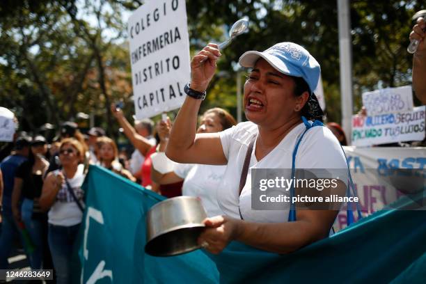 January 2023, Venezuela, Caracas: A woman bangs on a cooking pot during a protest by teachers, civil servants and pensioners who demanded a better...