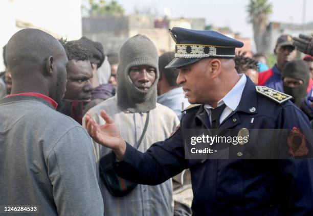 Moroccan policeman speaks with a group of African migrants in Casablanca on January 15, 2023. - Migrants threw stones that injured an officer and...