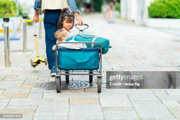 vater nimmt seine kinder für einen spaziergang durch die nachbarschaft - bollerwagen mann stock-fotos und bilder