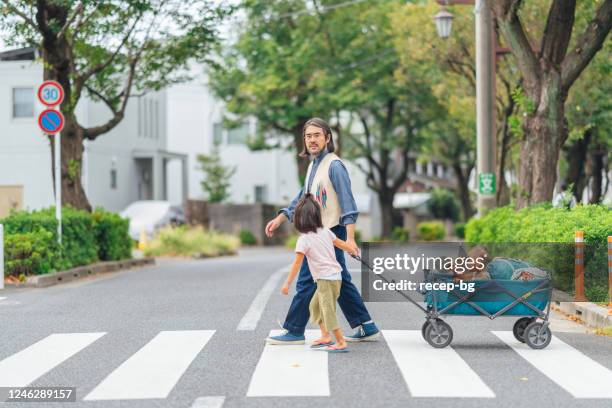 padre llevando a sus hijos a caminar por el barrio - vagón fotografías e imágenes de stock