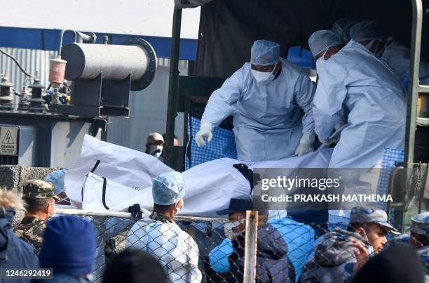 Nepal's army and volunteers carry the body of a victim who died in a Yeti Airlines plane crash in Pokhara on January 17, 2023. - The Yeti Airlines...