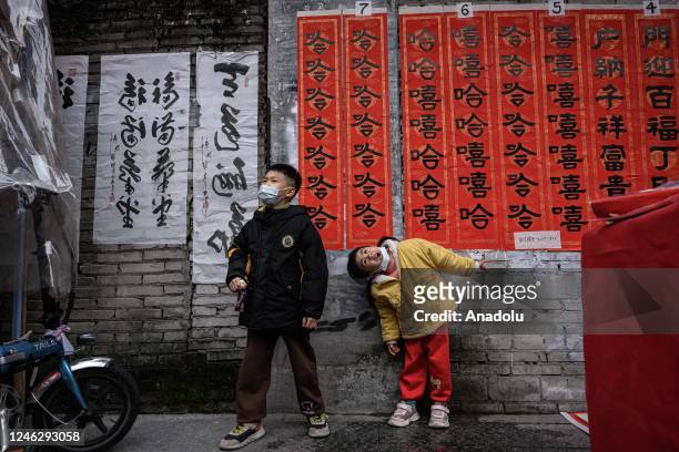 Children take photos with the spring festival couplets at Kuaizi Road in preparation for the upcoming Chinese Lunar New Year of the Rabbit on January...