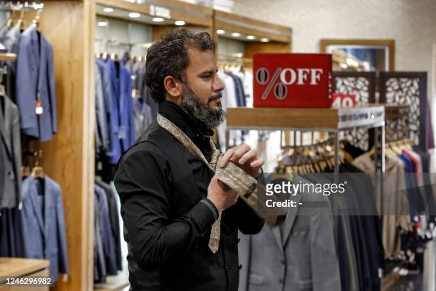 Man tries on a tie at a clothing shop in the north of Iran's capital Tehran on September 7, 2022. - After the fall of the shah in 1979, the Iranian...