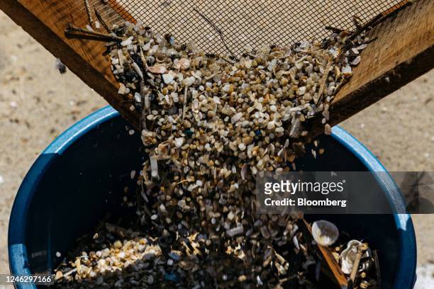 Local clean-up workers sift through beach sand to collect plastics washed ashore from a sunken container ship in Uswetakeiyawa, Sri Lanka, on...