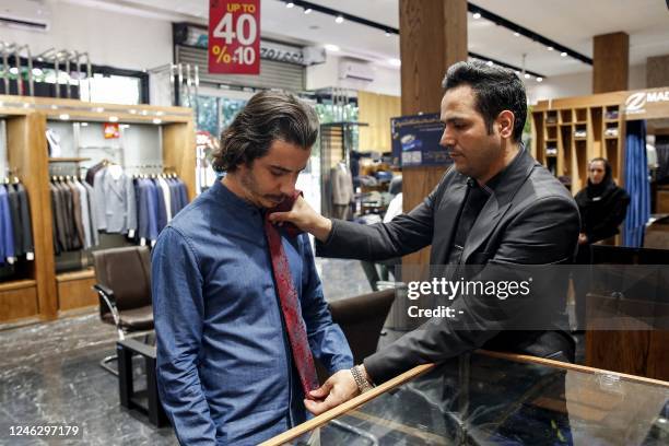 Shopkeeper assists a customer to try on a tie at a clothing shop in the north of Iran's capital Tehran on September 7, 2022. - After the fall of the...