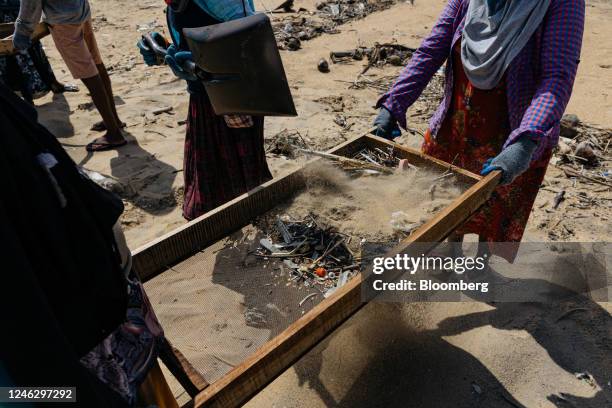 Local clean-up workers pour beach sand into a sieve to sort plastics and nurdles washed ashore from a sunken container ship in Uswetakeiyawa, Sri...