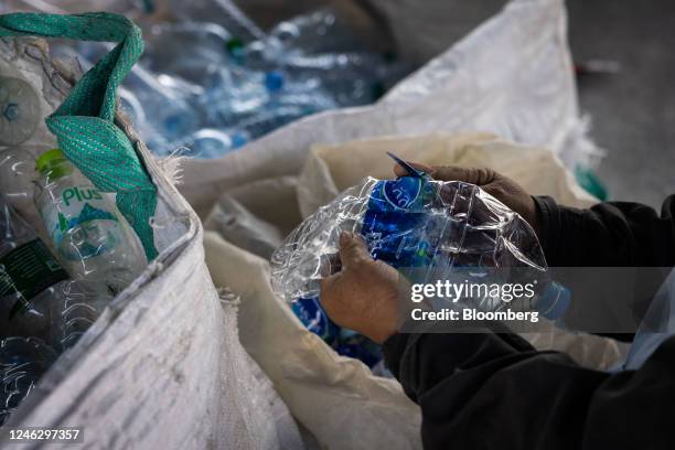 Volunteer removes the labels from plastic bottles for processing at a recycling center in Rayong, Thailand, on Wednesday, Dec. 14, 2022. Global...