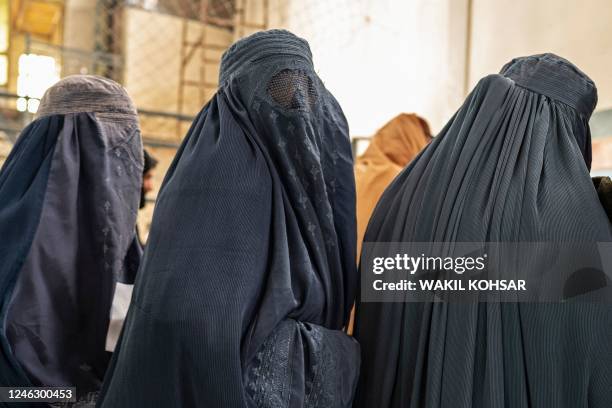 Afghan burqa-clad women stand in a queue as they wait to receive food aid from a non-governmental organisation at a gymnasium in Kabul on January 17,...