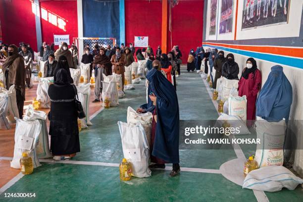 Afghan people stand with food aid being distributed by a non-governmental organisation at a gymnasium in Kabul on January 17, 2023. - At least three...
