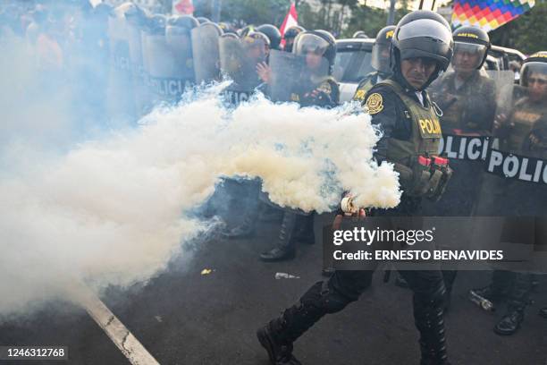 Police officer throws smoke while people protest against the government of Peruvian President Dina Boluarte in Lima on January 17, 2023. - Peruvian...