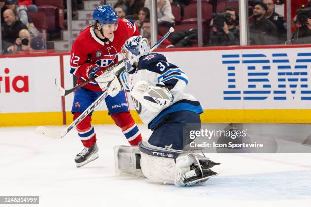 Cole Caufield of the Montreal Canadiens collides with Connor Hellebuyck of the Winnipeg Jets during the third period of the NHL game between the...