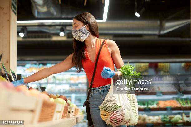een millenial klant die een herbruikbare boodschappentas in een supermarkt. - general views of shoppers during el buen fin mexicos black friday stockfoto's en -beelden