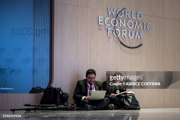 Members of a country's delegation in charge of communication are seating on the floor at the Congress centre during the World Economic Forum annual...
