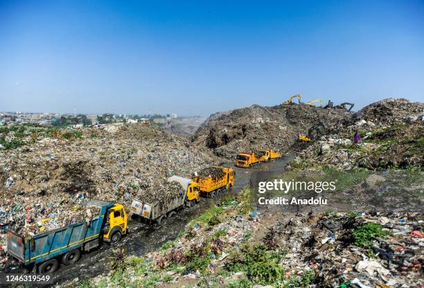 Dump trailers are seen as people collect items that are still intact to sell among waste material at Dandora, Nairobiâs main dump site, in Kenya on...