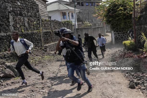 Members of the media run for cover as police disperse protesters during a demonstration against the East African Community Regional Force in Goma,...