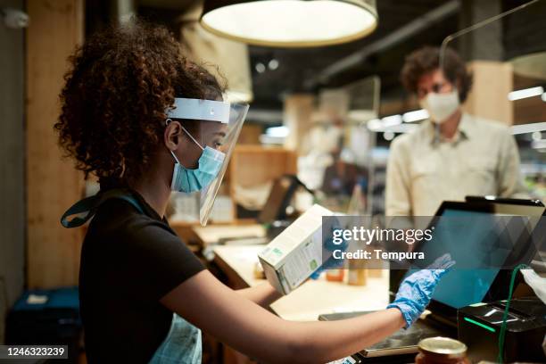 a grocery's cashier checking out products. - covid shopping stock pictures, royalty-free photos & images