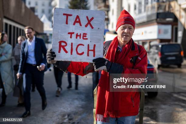 Phil White, a British millionaire poses with a placard reading: "Tax the rich" next to the Congress centre during the World Economic Forum annual...