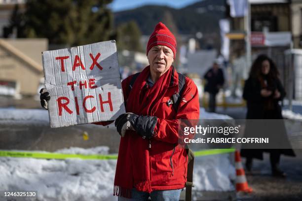 Phil White, a British millionaire poses with a placard reading: "Tax the rich" next to the Congress centre during the World Economic Forum annual...
