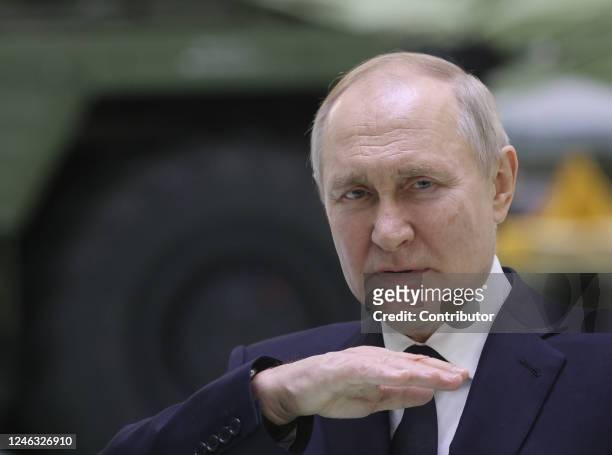 Russian President Vladimir Putin speaks during his meeting with workers at the Obukhov State Plant as a military vehicle seen in the background on...