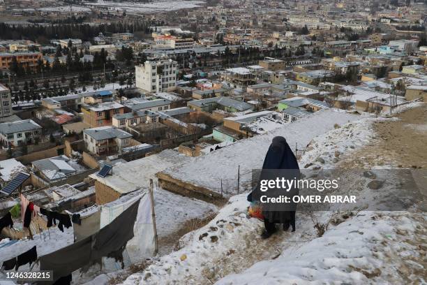 Woman walks down at a path during a cold winter day in Fayzabad of Badakhshan province on January 18, 2023. - At least 70 people have died in a wave...