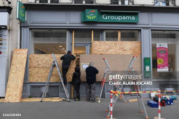 Workers board up the windows of an insurance group branch located on the route of a demonstration, on the eve of nationwide strikes and protests...