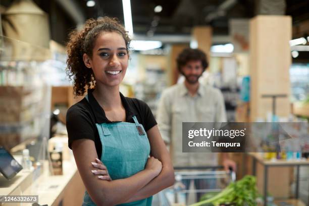 one young female cashier portrait looking at camera - supermarket queue stock pictures, royalty-free photos & images