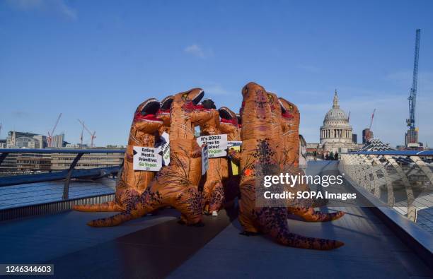 Activists wearing dinosaur costumes hold placards which state 'Eating meat is primitive' and 'It's 2023, time to evolve' during the demonstration on...