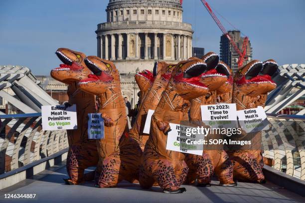 Activists wearing dinosaur costumes hold placards which state 'Eating meat is primitive' and 'It's 2023, time to evolve' during the demonstration on...