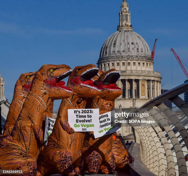 Activists wearing dinosaur costumes hold placards which state 'Eating meat is primitive' and 'It's 2023, time to evolve' during the demonstration on...