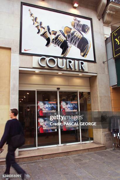 Un jeune homme passe, le 07 septembre 2000 à Paris, devant un magasin Courir, spécialisé dans les articles de sport, appartenant à la société Rallye,...